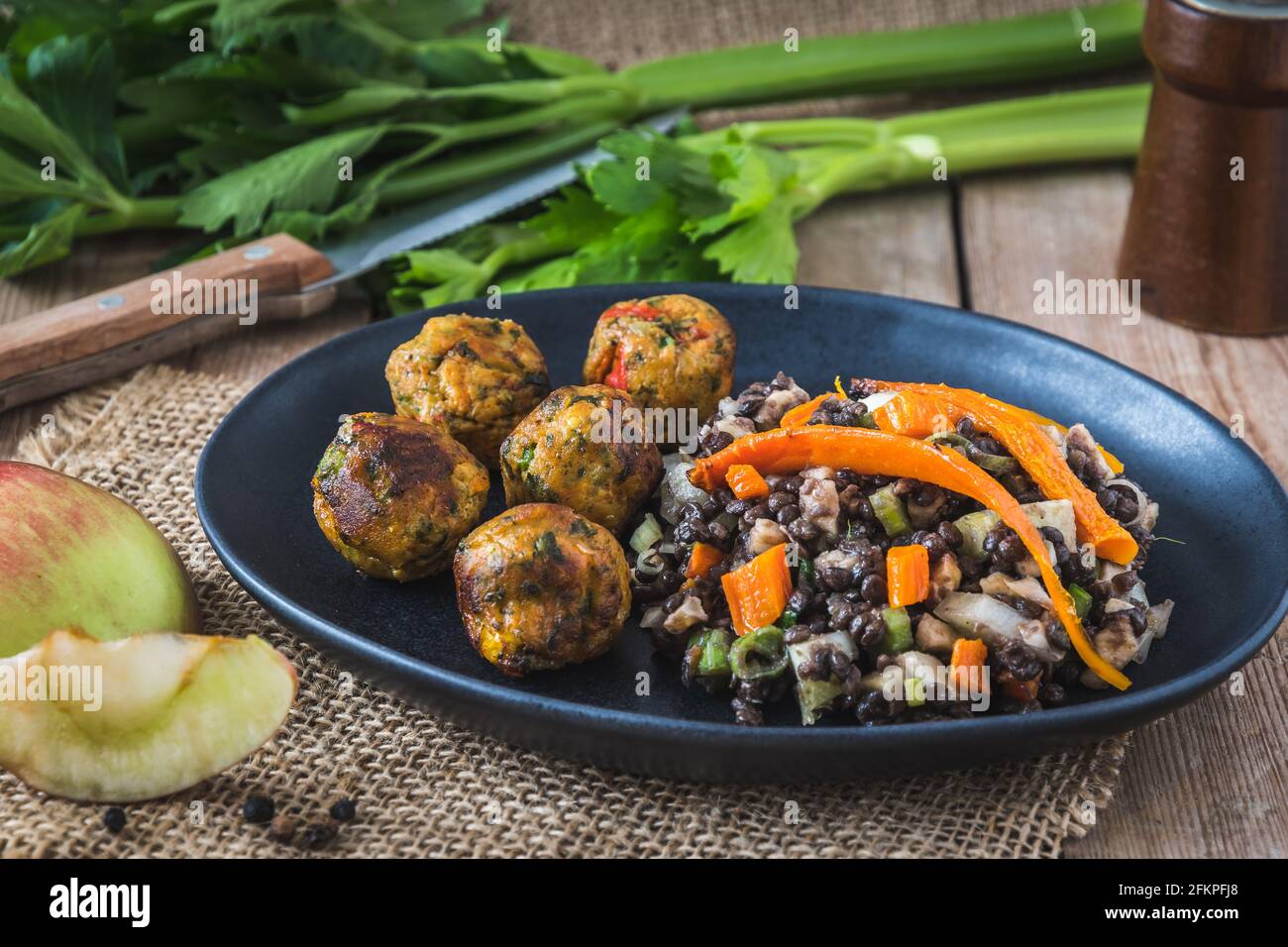 Palle di verdure arrosto con insalata di lenticchie su piatto nero su tavola di legno, concetto di cibo vegano Foto Stock