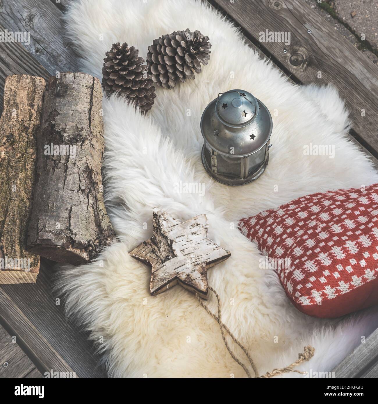 Veranda in legno con pelle di agnello, cuscini natalizi rossi e bianchi, lanterna e tronchi, vista dall'alto obliqua Foto Stock