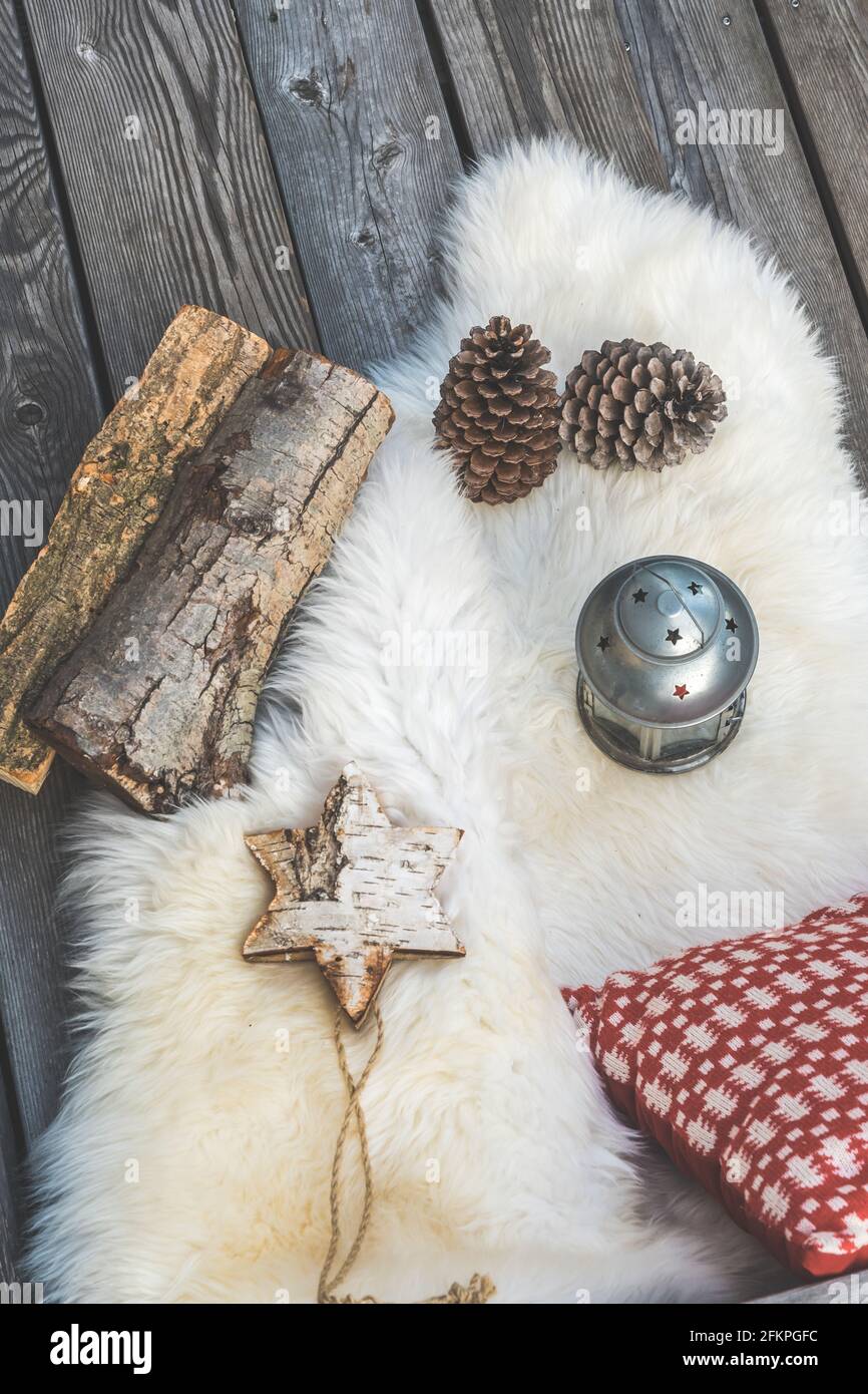 Veranda in legno con pelle di agnello, cuscini natalizi rossi e bianchi, lanterna e tronchi, vista dall'alto verticale Foto Stock