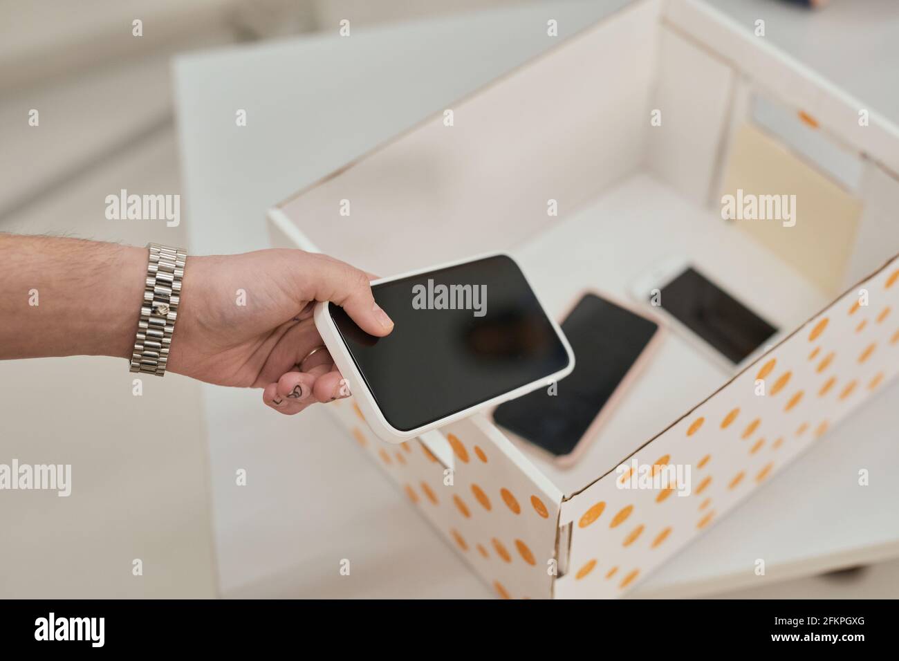Primo piano di un adolescente irriconoscibile mettere smartphone in scatola in classe no gadget a scuola, spazio di copia Foto Stock