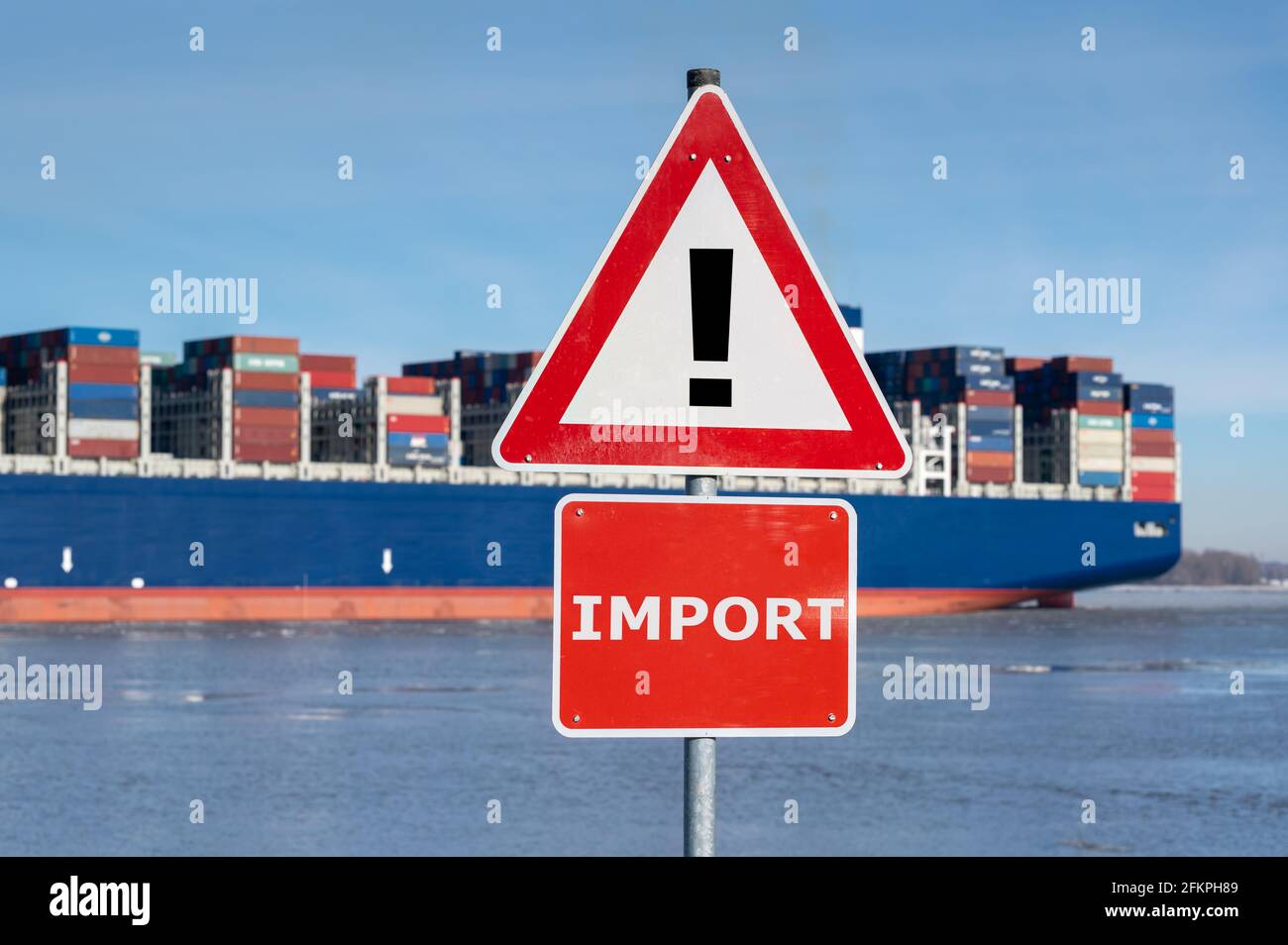 Simbolo di una crisi economica. Un segnale di avvertimento con la parola 'import' davanti ad una nave enorme del contenitore. Foto Stock