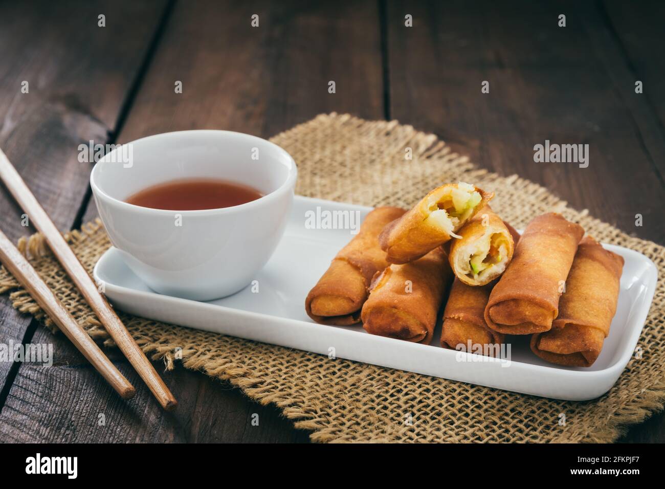 Mini involtini primavera con salsa piccante dolce e bastoncini un tavolo rustico in legno Foto Stock