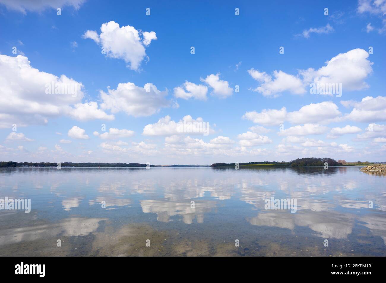 Superficie specchiata del lago artificiale di Rutland cielo blu con nuvole Riflessioni Rutland acqua vicino Oakham Rutland Inghilterra GB Europa Foto Stock