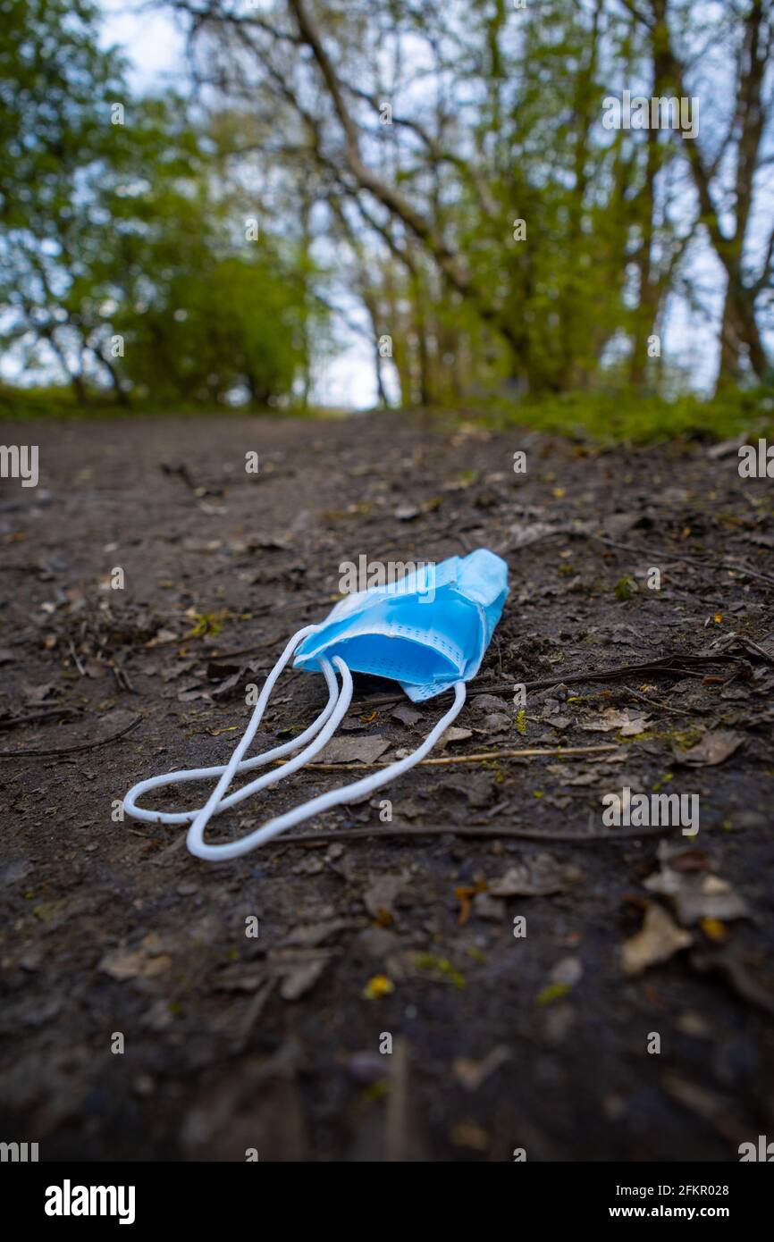 maschera di faccia scartata lasciata sul sentiero nel bosco protezione della covide Foto Stock