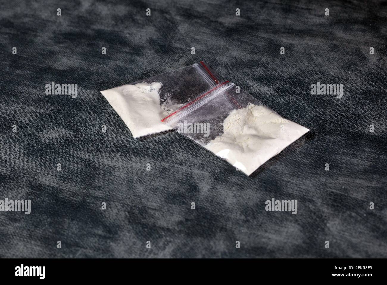 Sacchetti di plastica trasparenti con polvere bianca, cocaina, velocità o altre droghe su sfondo grigio con spazio di copia, trattare, droga, junky, concetto di dipendenza Foto Stock