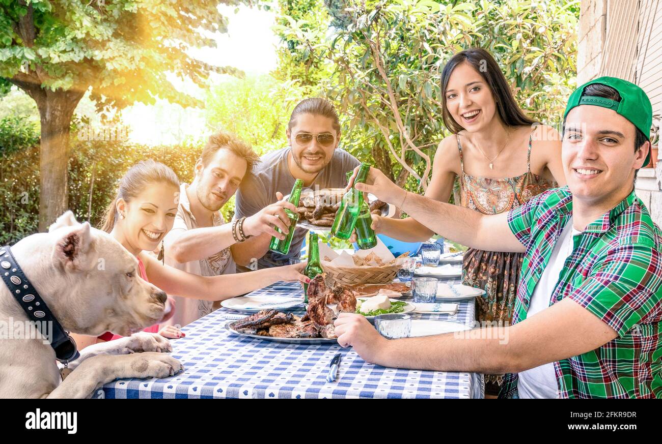 Gruppo di amici felici che mangiano e tostano al barbecue in giardino - concetto di felicità con i giovani a casa godendo cibo insieme Foto Stock