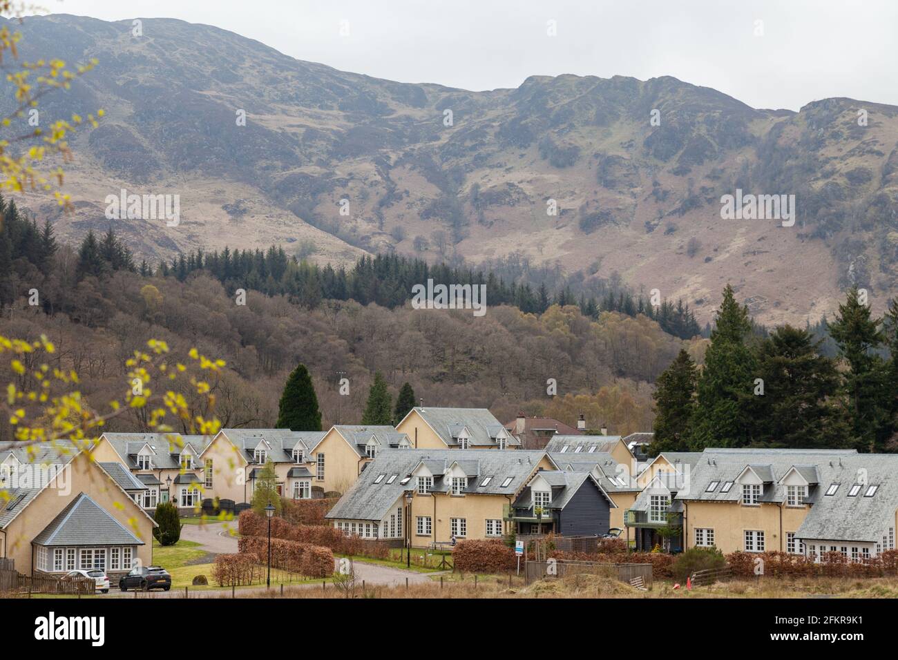 Nuove case a St Fillans con colline rocciose sullo sfondo. Foto Stock