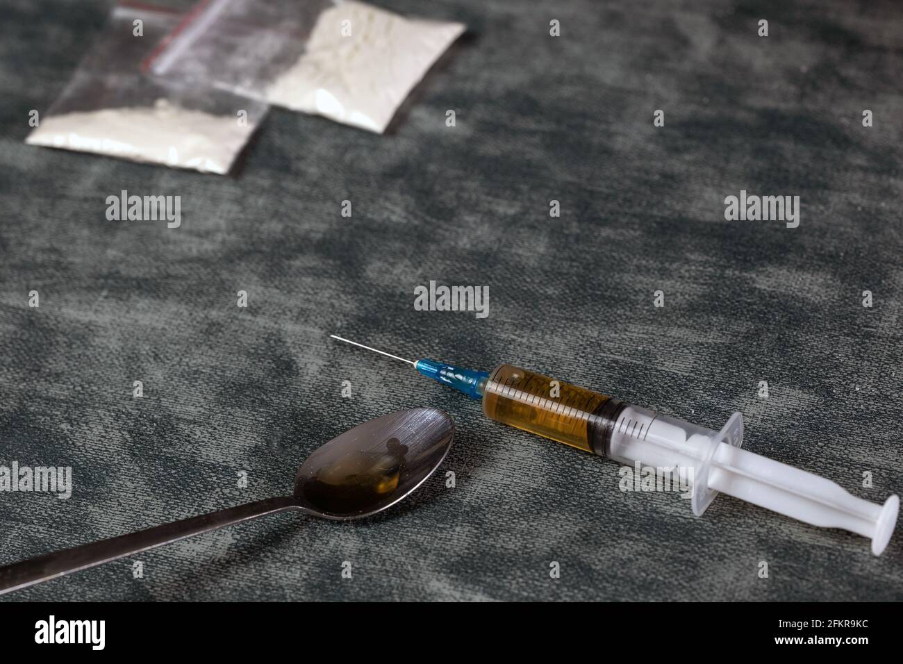 Concetto di aggiunta di droga, siringa di droga con eroina e cotto su cucchiaio su sfondo grigio con spazio di copia, addict, junky, salute, droga concetto di fondo Foto Stock