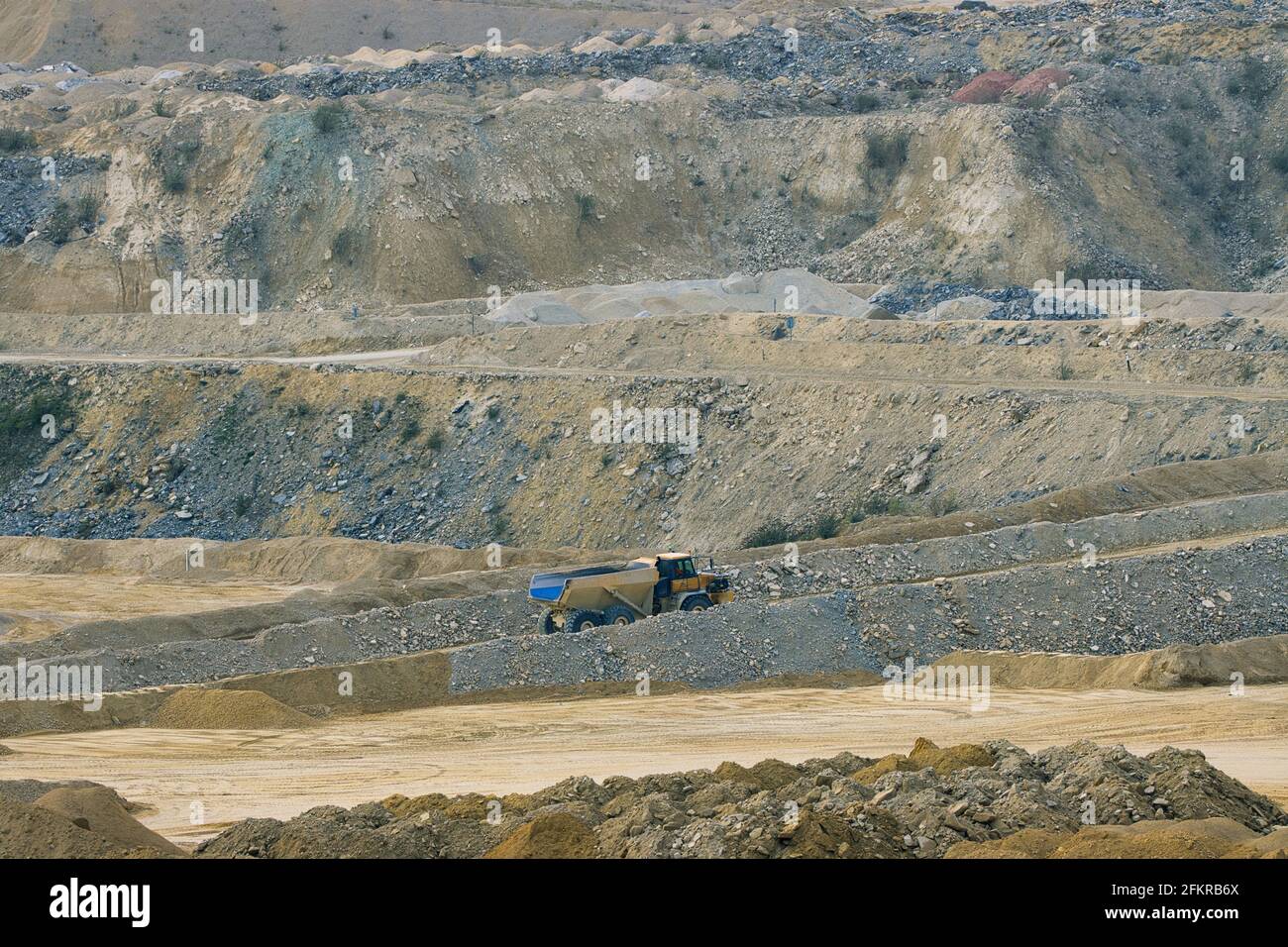 Un grande camion articolato dwared dalle scogliere in una cava enorme. Inghilterra, Regno Unito. Foto Stock
