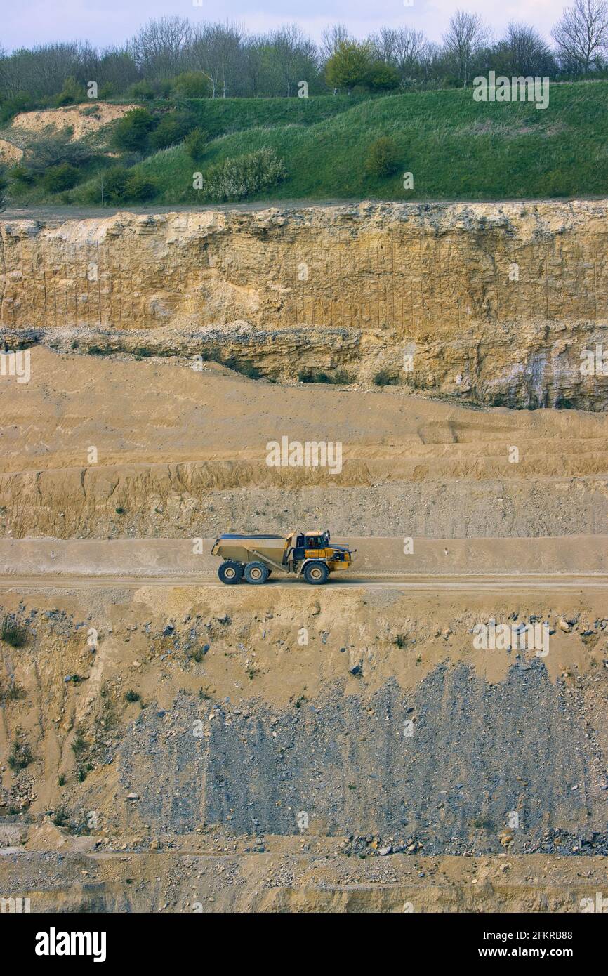 Un grande camion articolato dwared dalle scogliere in una cava enorme. Inghilterra, Regno Unito. Foto Stock