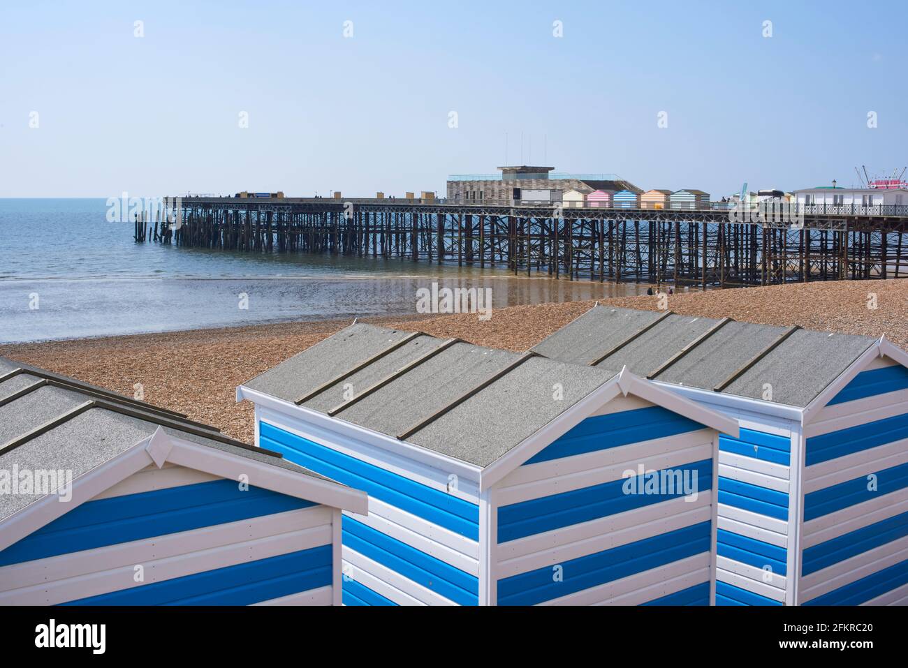 Hastings Pier e capanne sulla spiaggia sul lungomare, East Sussex, South East England Foto Stock