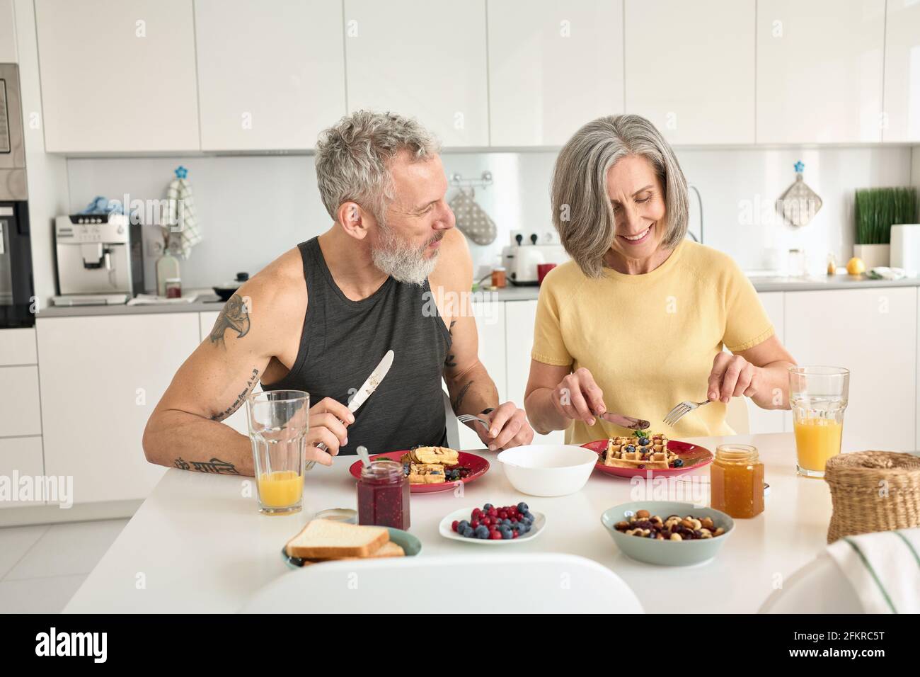 Felice sano fit matura famiglia coppia con la colazione sedersi al tavolo da cucina. Foto Stock