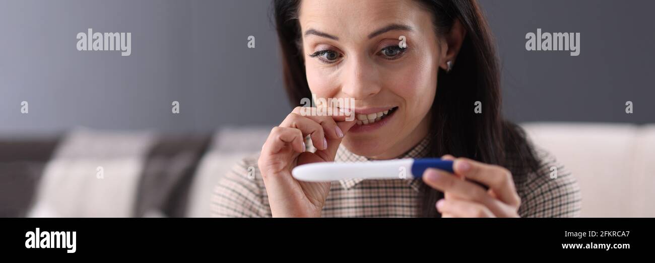 Donna sorpresa che guarda il closeup test di gravidanza Foto Stock