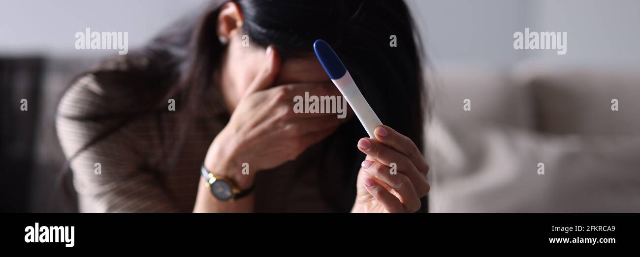 Donna triste che tiene il test di gravidanza in mano Foto Stock