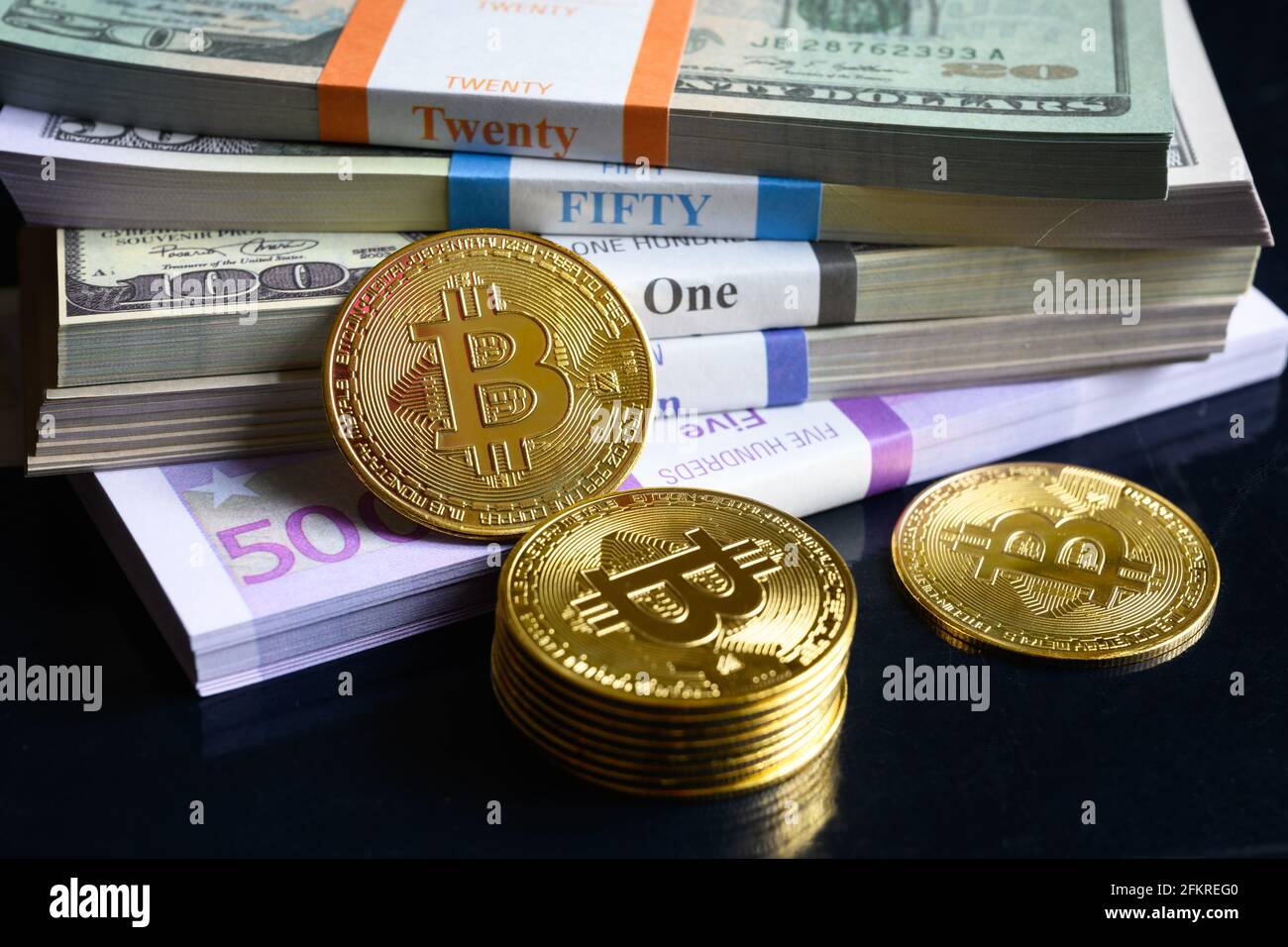 Bitcoin e pile di denaro, criptovaluta digitale virtuale bitcoin btc con pila di contanti. Gran parte delle banconote in euro e dollari USA e delle monete in oro. Concetto di Foto Stock