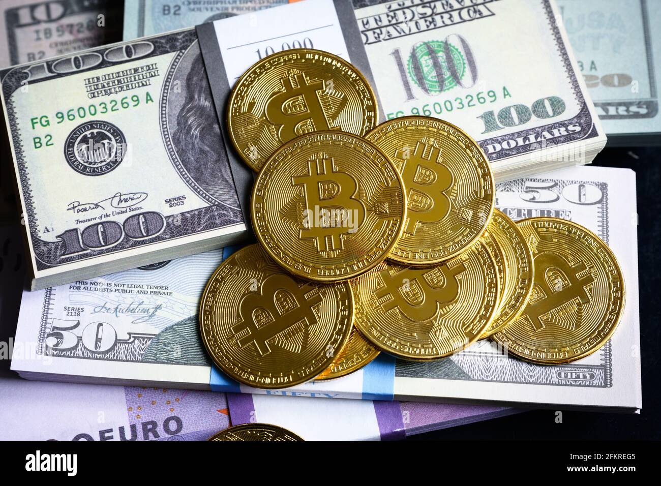 Bitcoin e pile di denaro, criptovaluta digitale virtuale bitcoin btc con pila di contanti. Gran parte delle banconote in euro e dollari USA e delle monete in oro. Concetto di Foto Stock