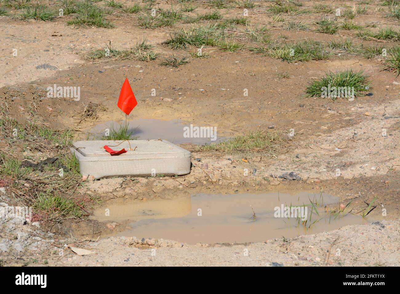 Allarme con bandierina rossa in cantiere che indica le linee sotterranee dove non scavare Foto Stock