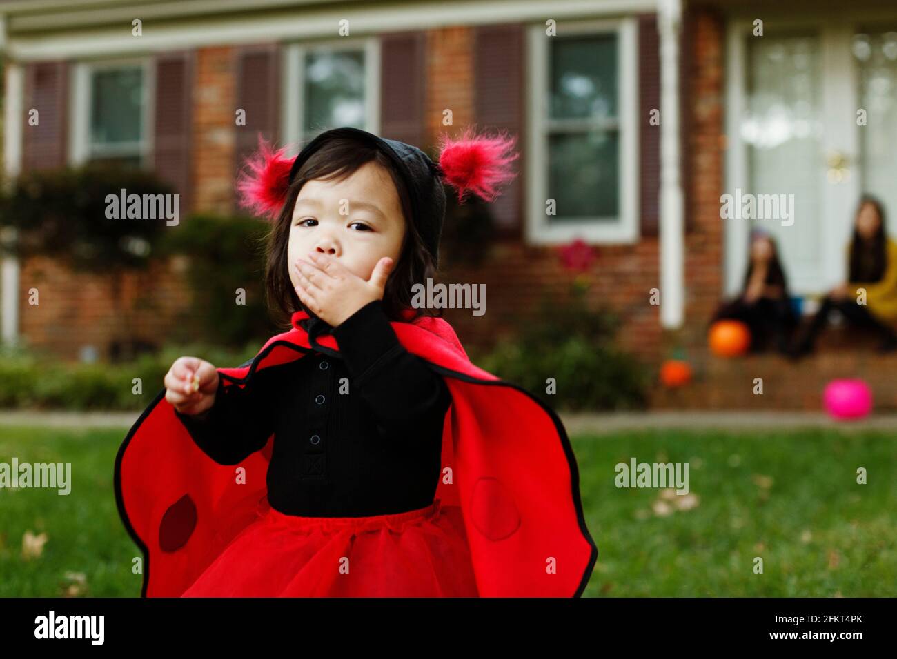 Ragazza vestita come coccinella con la mano sulla bocca Foto Stock