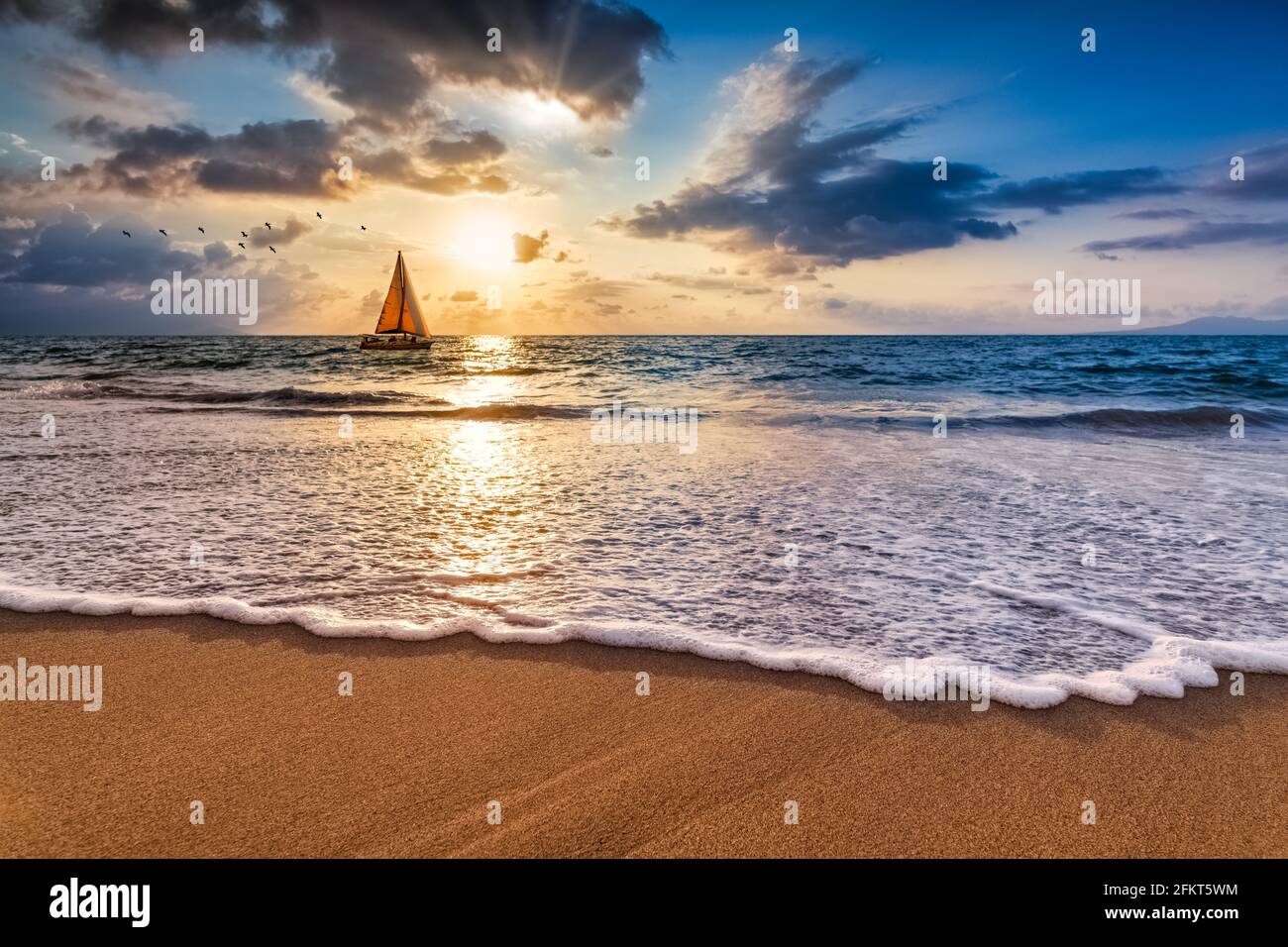 Una barca a vela sta navigando lungo l'oceano contro UN colorato Ocean Sunset Sky come un'onda dolce rotola a Shore Foto Stock