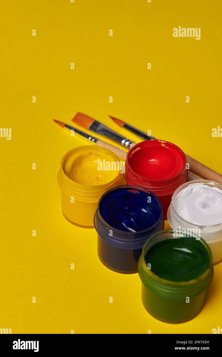 vasi colorati di vernice su sfondo giallo Foto Stock