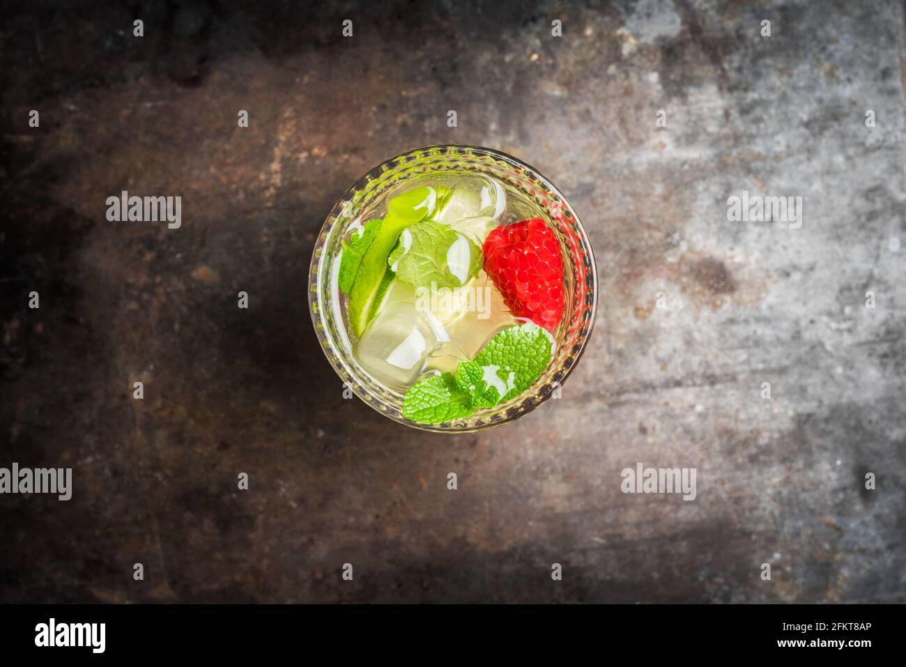 Cocktail estivo vecchio stile a base di gin con lampone e lime su sfondo rustico. Messa a fuoco selettiva. Profondità di campo poco profonda. Foto Stock