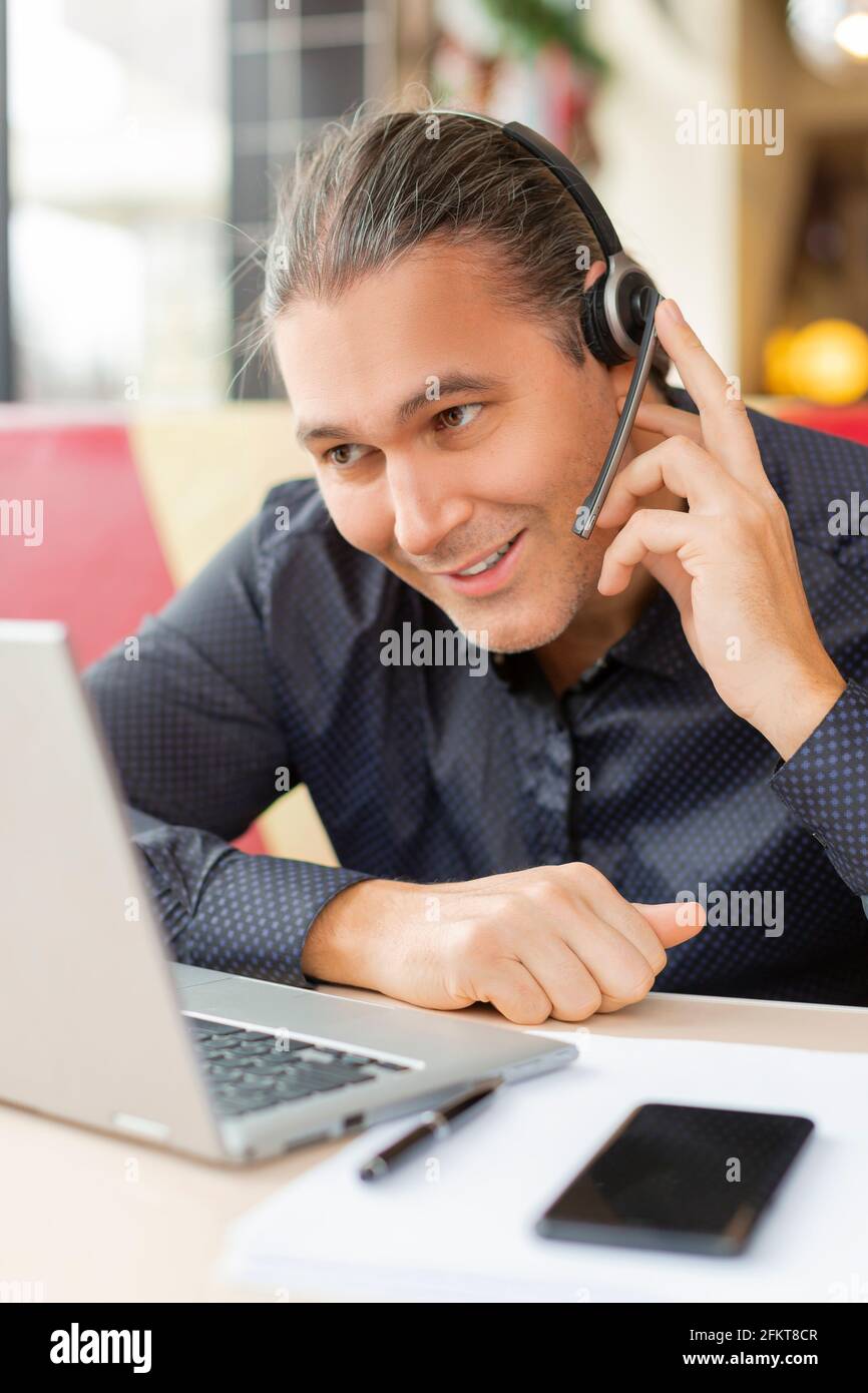Ritratto di un uomo di mezza età durante la videochiamata online. È seduto davanti al monitor del computer portatile e sorridente. Concetto di tecnologie aziendali moderne. Foto Stock