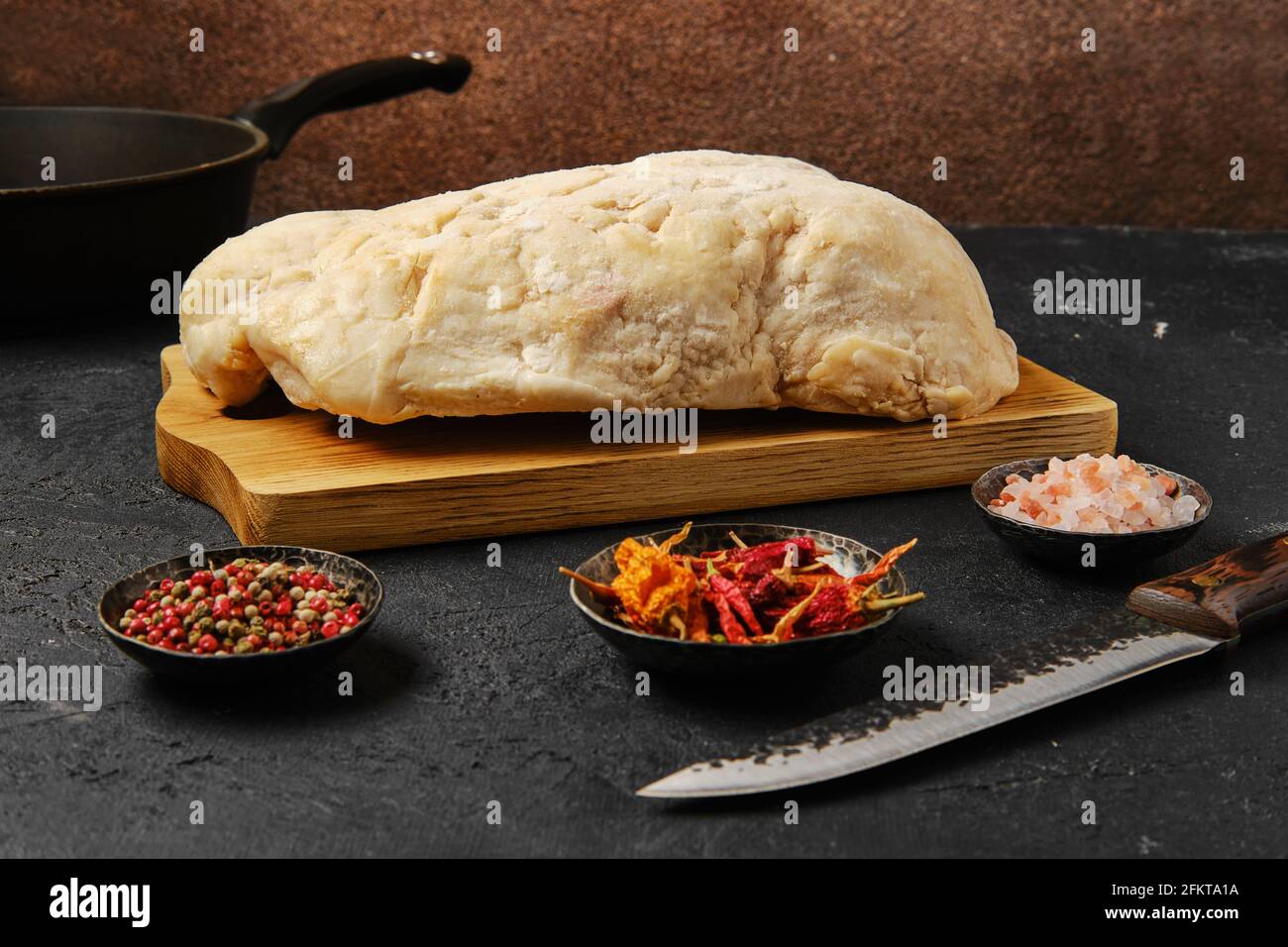 Coda di grasso di agnello sul tavolo da cucina con sale e pepe Foto Stock