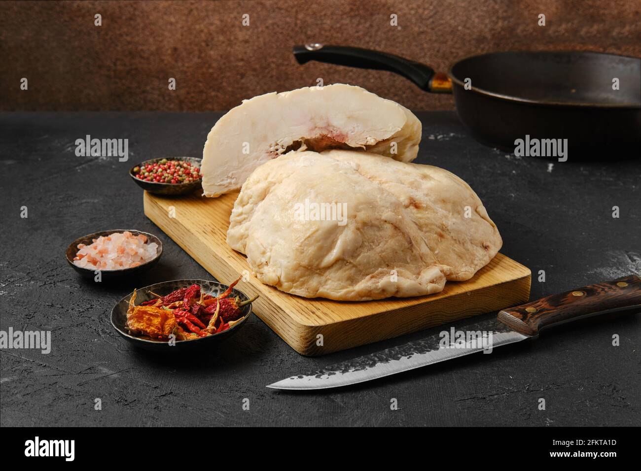 Tagliare la coda di grasso di agnello sul tavolo da cucina con sale e. pepe Foto Stock