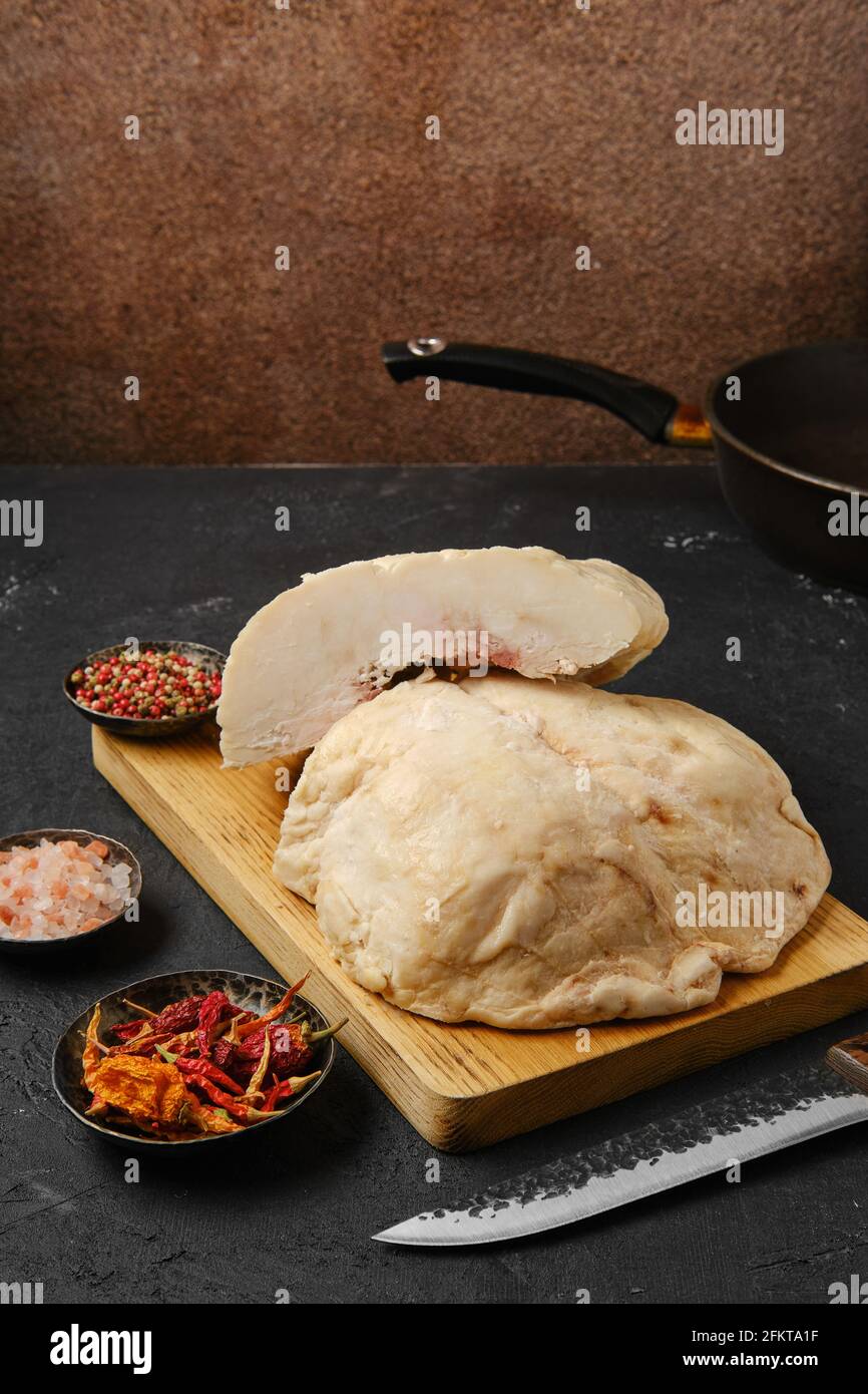 Tagliare la coda di grasso di agnello sul tavolo da cucina con sale e. pepe Foto Stock