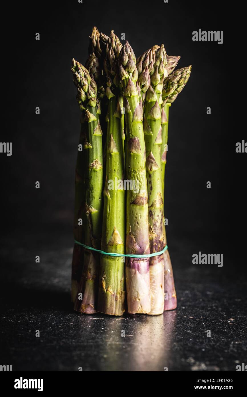 Asparagi verdi crudi freschi su tavola nera. Foto Stock