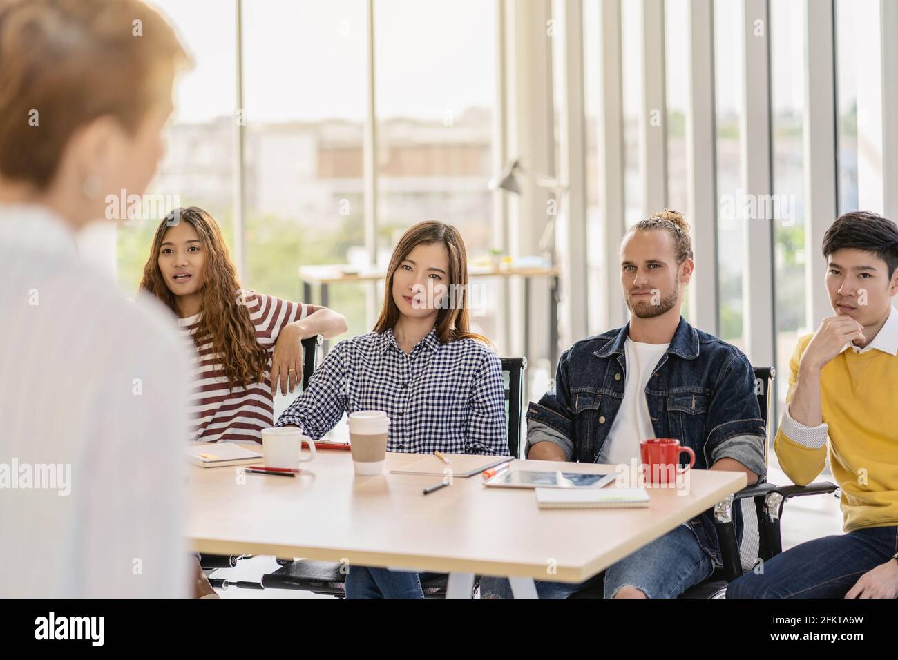 RIEW vista di Manager donna che parla seriamente con il gruppo Di membri asiatici e multietnici del team Business con tuta casual in azione seria quando il progetto i Foto Stock