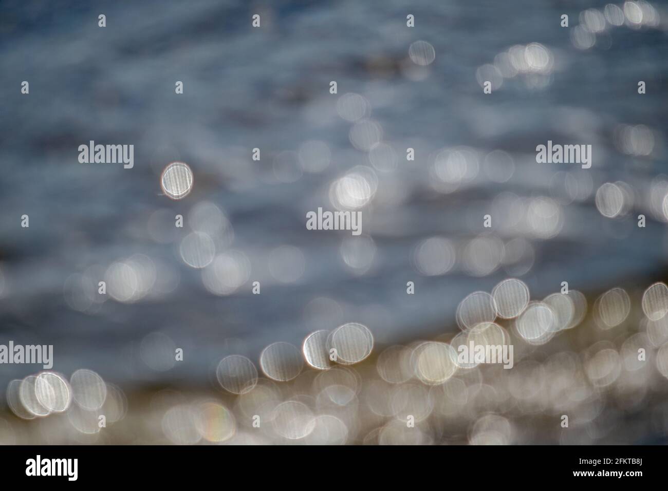 Il sole non focalizzato si riflette sull'acqua delle spiagge di Marbella, Spagna Foto Stock