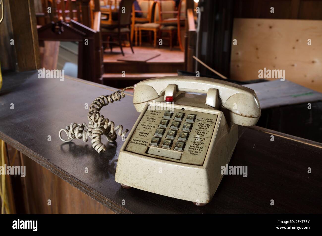 Un telefono di cortesia grugnoso all'interno di una lobby dell'hotel abbandonata. Questo edificio è stato demolito e non esiste più. Foto Stock