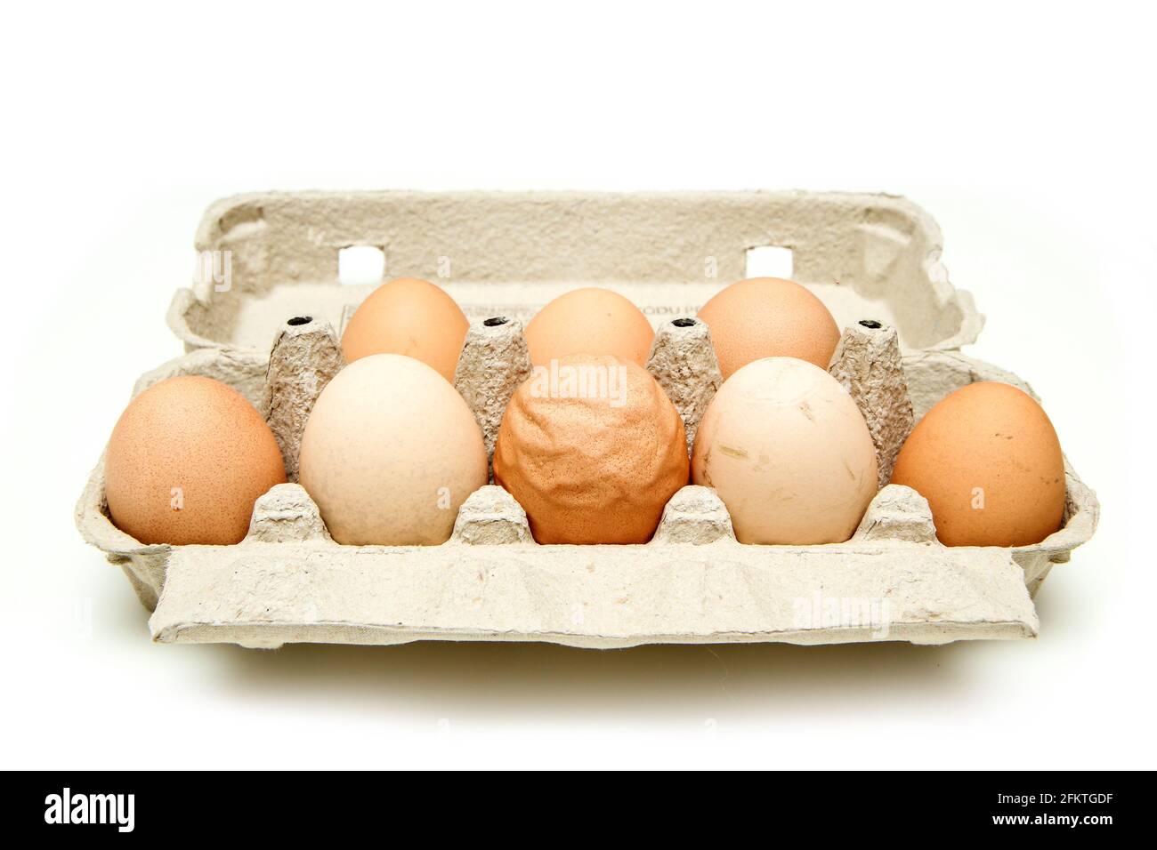 L'uovo biologico con gusci d'uovo ruvidi e ondulati tra le altre uova buone. Isolato su sfondo bianco. Foto Stock