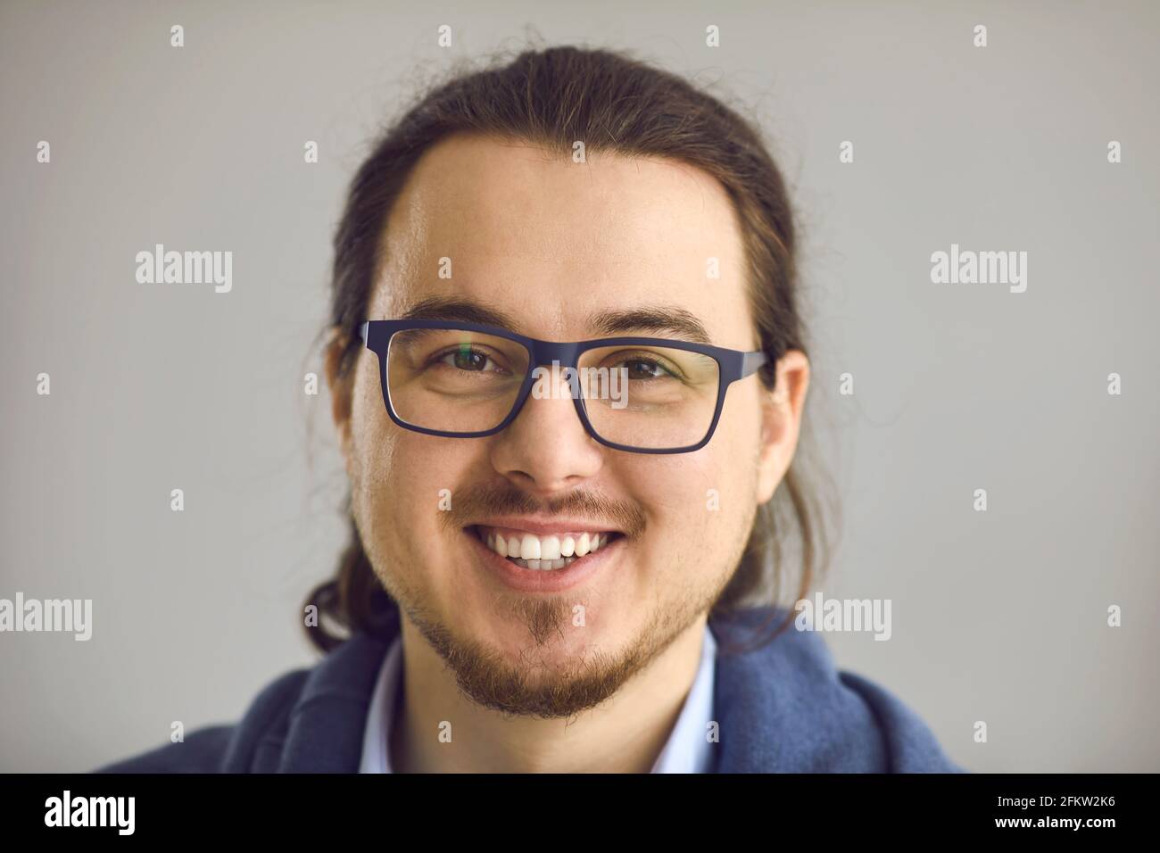 Studio ritratto di felice intelligente giovane uomo in occhiali con sorriso aperto e cordiale Foto Stock