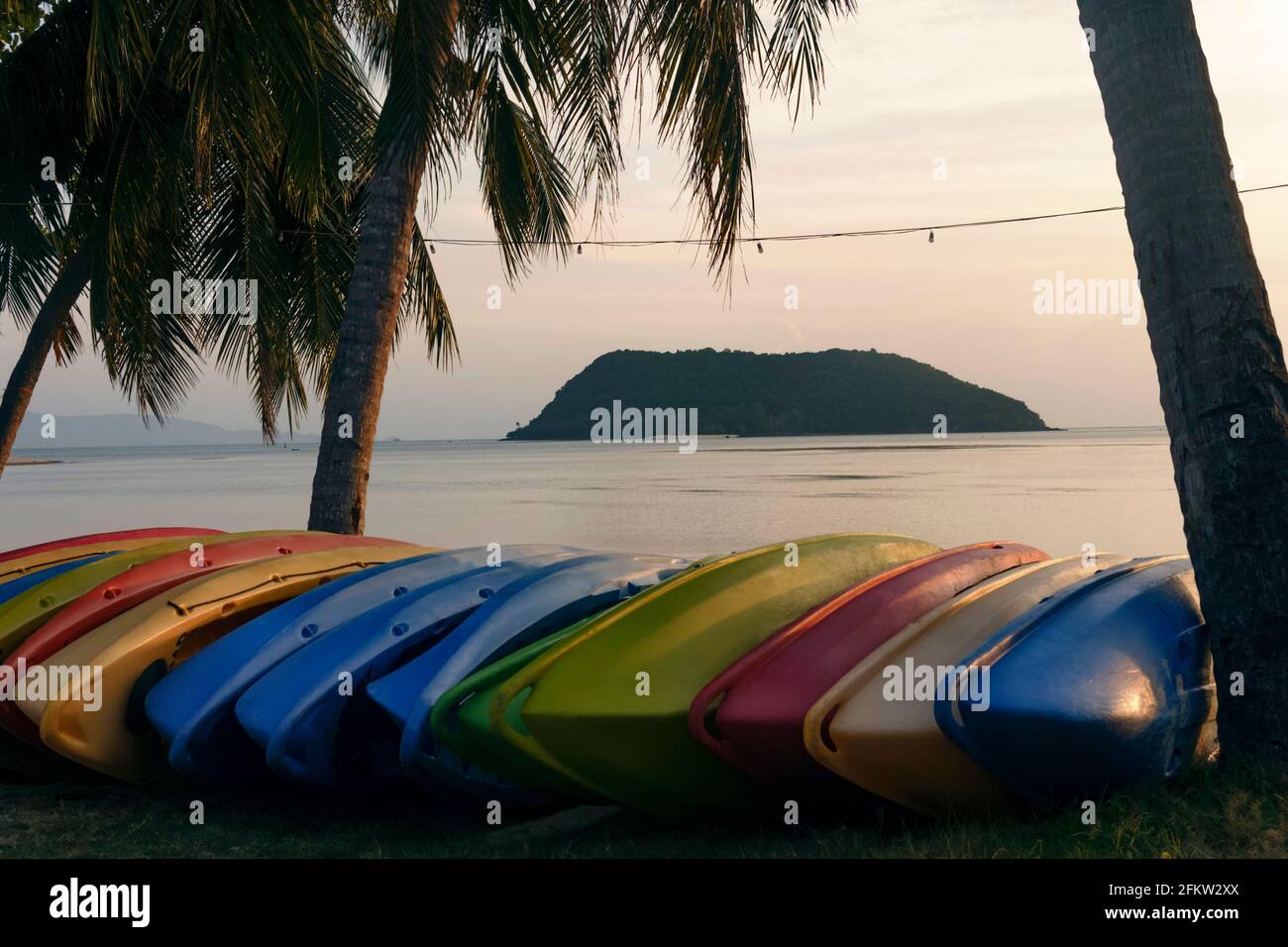 Le barche da rafting si trovano lungo la spiaggia. Barche multicolore sulla spiaggia che si affaccia su una piccola isola. Foto Stock