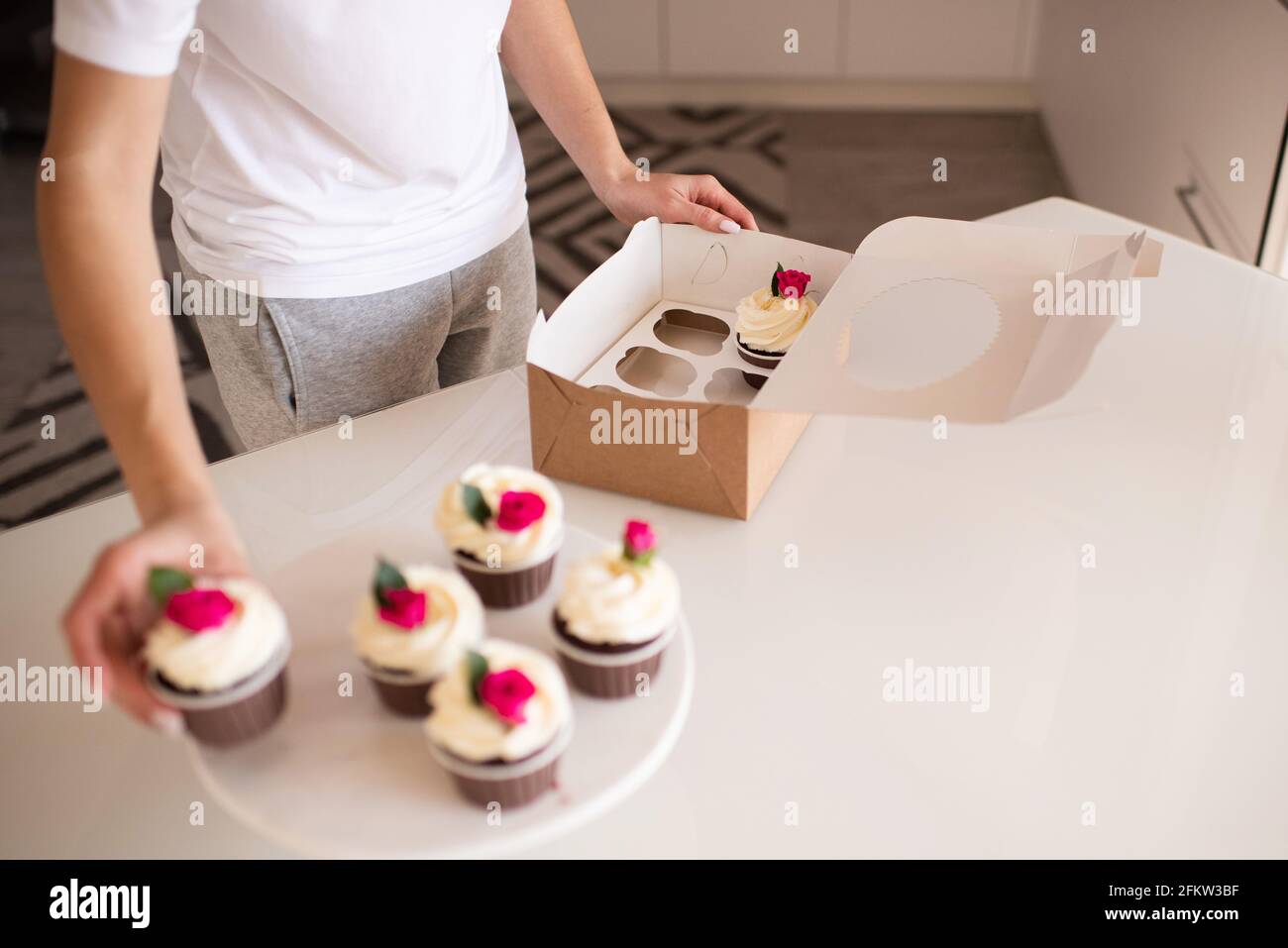 Cute baby girl 2-3 anni mangiando gustosi cupcakes con crema in cima alla cucina interna. Infanzia. Messa a fuoco selettiva. Foto Stock