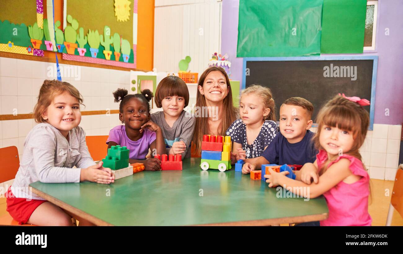 Felice insegnante di asilo e bambini multiculturali in asilo internazionale Foto Stock