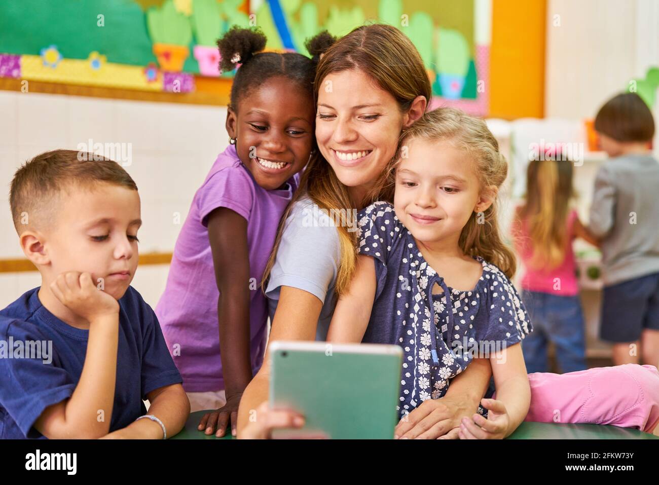 I bambini e i bambini prendono un selfie con il computer tablet in asilo o centro di assistenza post-scuola Foto Stock