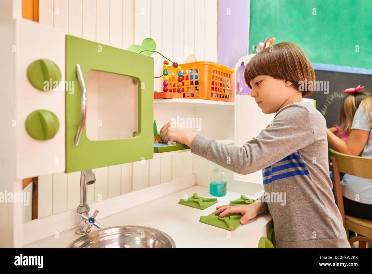 Ragazzo pulizia e riassetto della cucina in asilo per pulizia e doveri Foto Stock