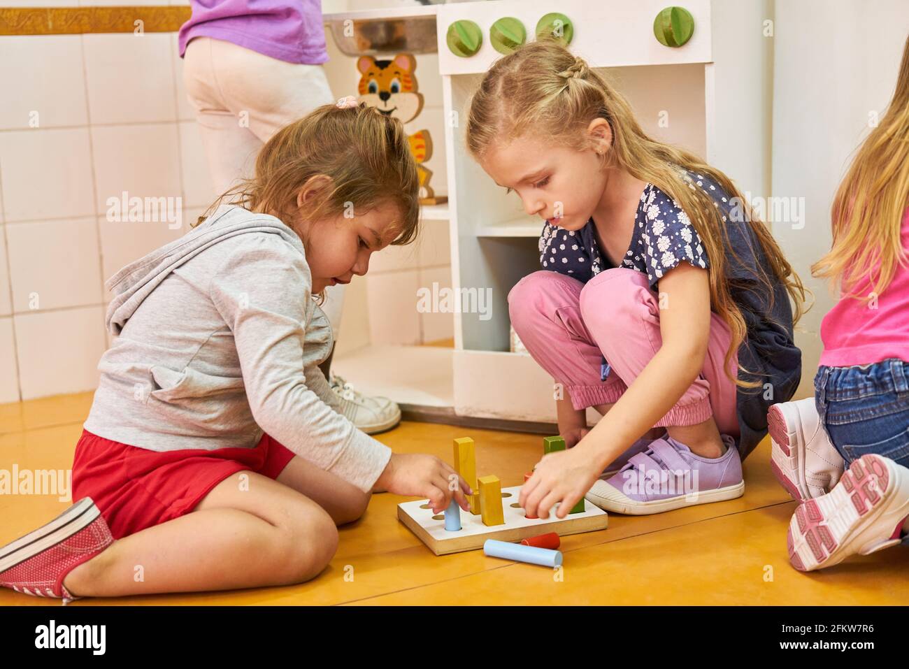 Due ragazze giocano un gioco di pedaggio con i blocchi di costruzione dentro asilo o centro di assistenza post-scolastica Foto Stock