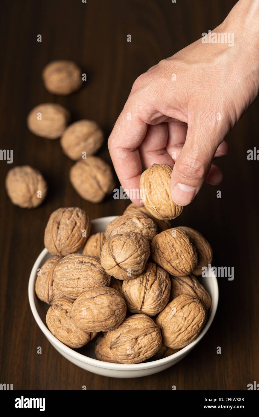 Mano dell'uomo che raccoglie una noce da una ciotola Foto Stock