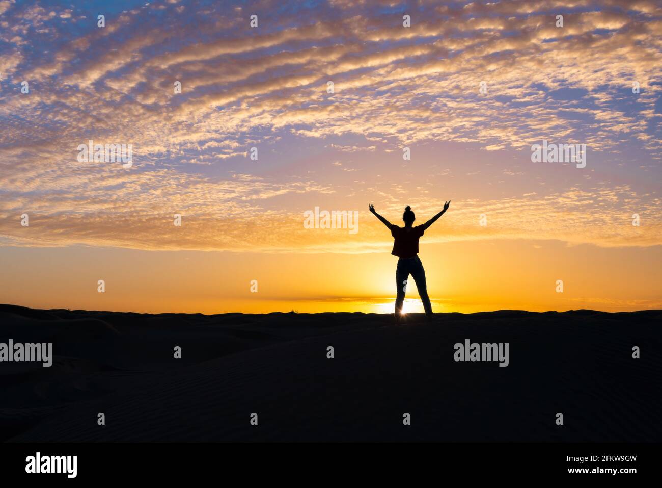 Silhouette di una giovane donna sicura in piedi al tramonto. Posa di potenza. Foto Stock