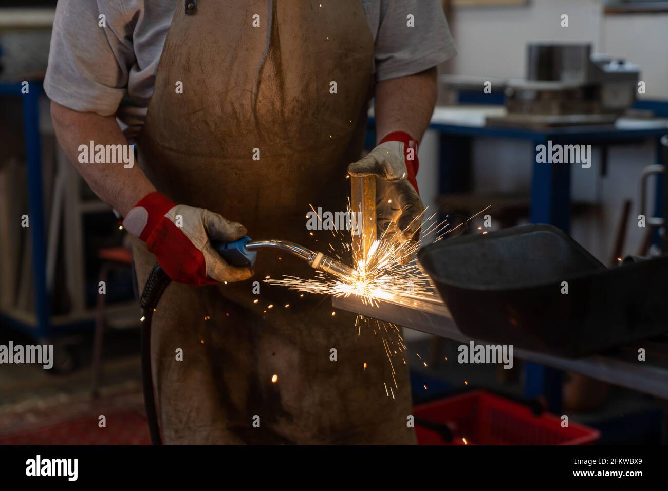 Un lavoratore di metallo che salda e costruisce un telaio di metallo per un patio giardino Foto Stock