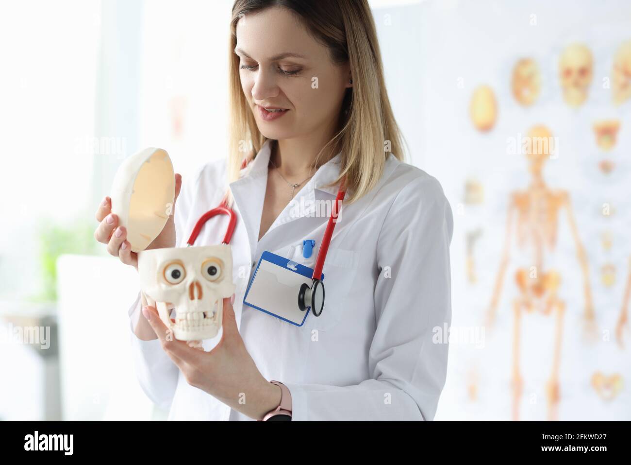 La dottoressa in camice bianco sta tenendo manichino di essere umano cranio Foto Stock