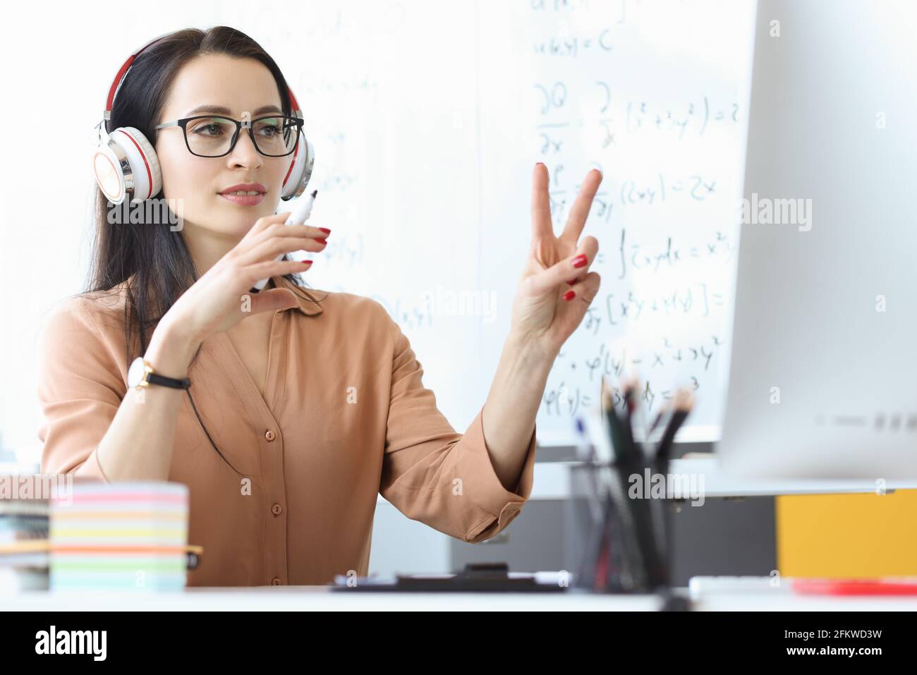 Ritratto di insegnante femminile in cuffie che conduce lezioni online a distanza Foto Stock