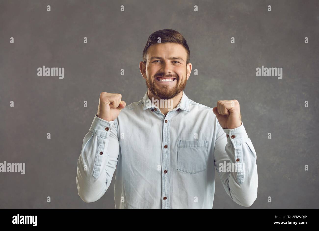Uomo con gli occhi chiuso pugno clenching festeggiando successo in piedi studio scatto Foto Stock