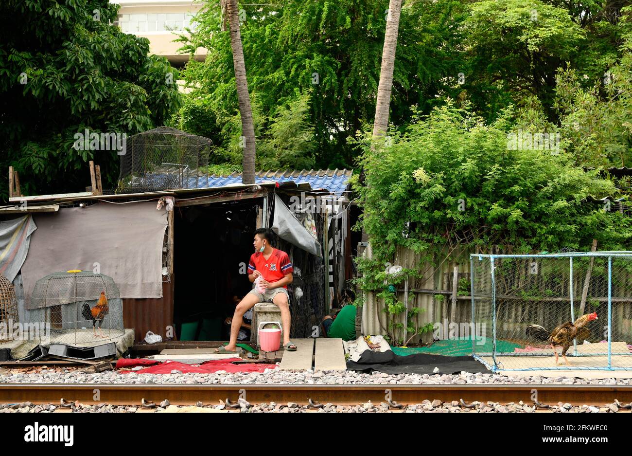 Un uomo si siede vicino ai suoi gabbie gabbie lungo la ferrovia track.Bangkok città abitanti che vivono lungo la linea ferroviaria. La ferrovia di Stato della Thailandia (SRT) viaggia dalla stazione centrale di Bangkok a Hua Lamphong ad est della capitale e si collega a Chachoengsao, 82 km da Bangkok lungo questa linea. (Foto di Paul Lakatos / SOPA Images/Sipa USA) Foto Stock