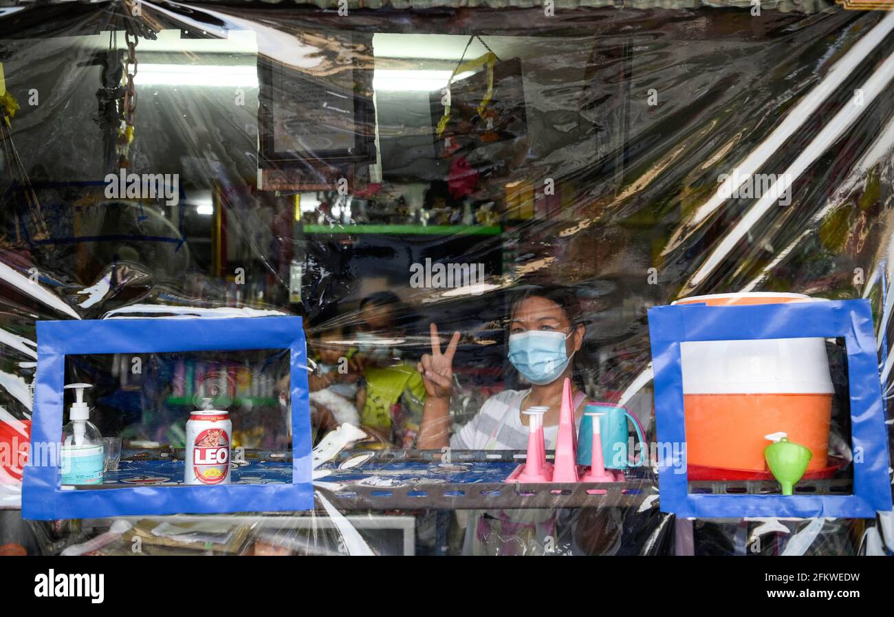 Una donna che indossa una maschera facciale posa attraverso un foglio di plastica di fronte al suo negozio lungo la linea ferroviaria.Bangkok città abitanti che vivono lungo la linea ferroviaria. La ferrovia di Stato della Thailandia (SRT) viaggia dalla stazione centrale di Bangkok a Hua Lamphong ad est della capitale e si collega a Chachoengsao, 82 km da Bangkok lungo questa linea. Foto Stock