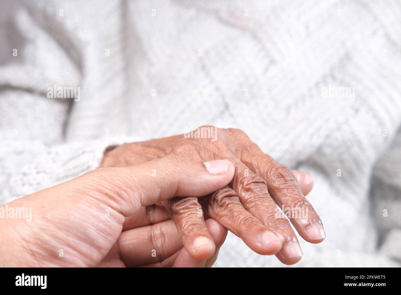 dettaglio di un giovane uomo che tiene la mano di un anziano donne Foto Stock